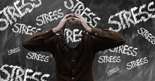Image of a person with their head in their hands and the word stress in the background. 