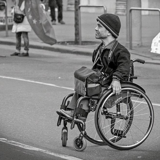 Black and white photo of a glum-looking wheelchair user.