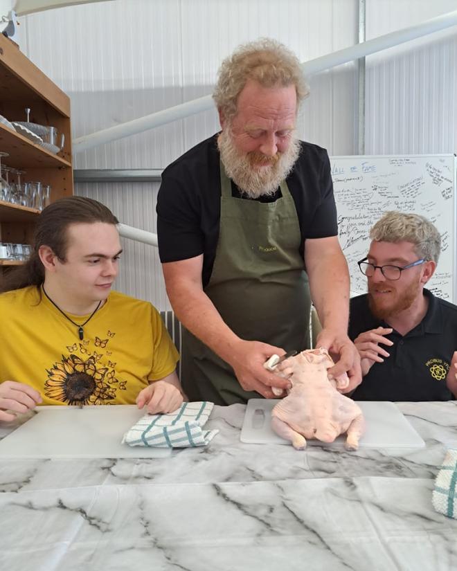 A photo of chef Adrian demonstrating how to butcher a chicken. 